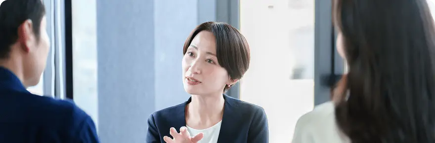 女性スタッフが2人の顧客に向けて説明をしている様子