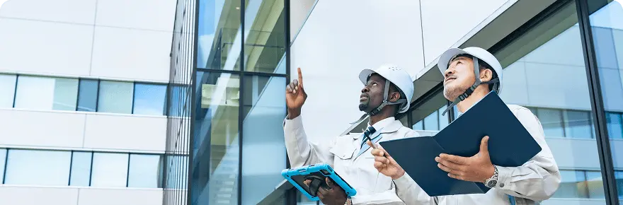 ヘルメットを着用した2人の作業員が建物を見上げながら点検中
