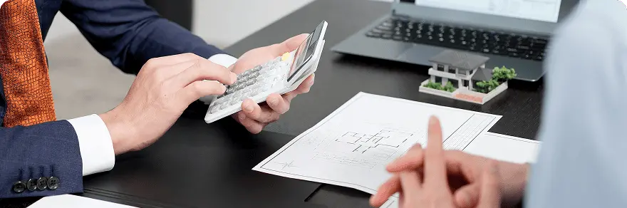 設計図と模型を前に、不動産や住宅に関する資金計画の打ち合わせを行う様子